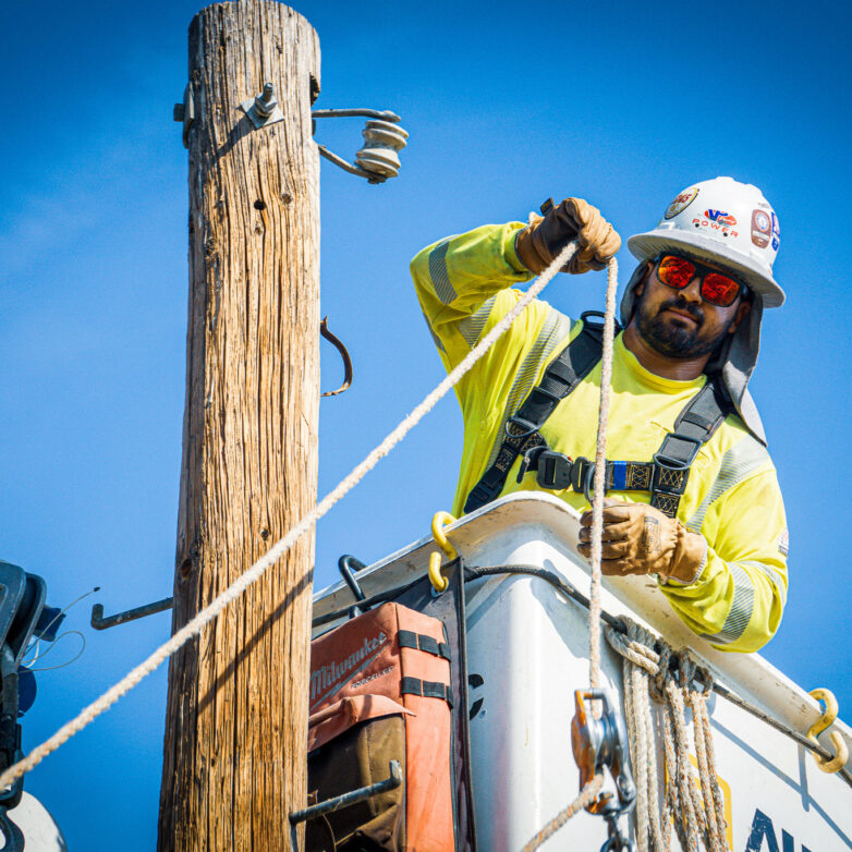 Close-up view of construction worker on a bucket truck beside a power line
